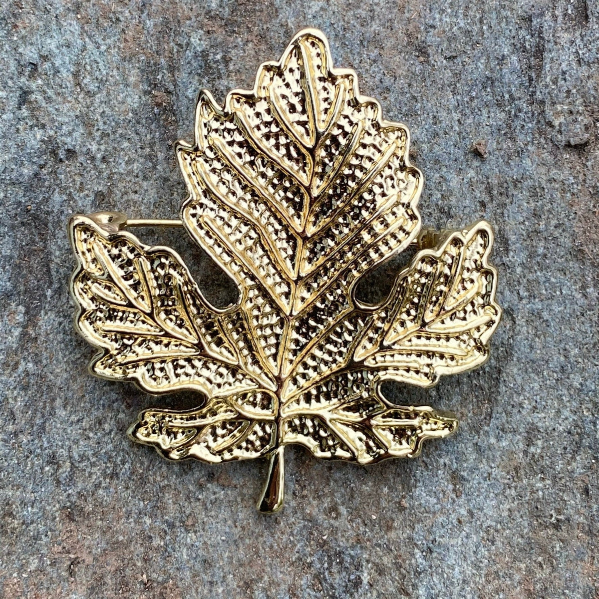 Ornate gold leaf brooch on stone background for LARP.