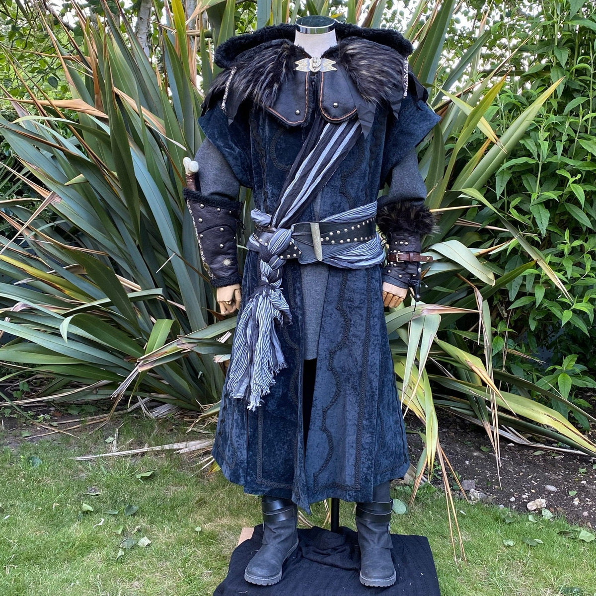 Dark blue medieval LARP outfit with hood, vambraces, scarf, and boots.