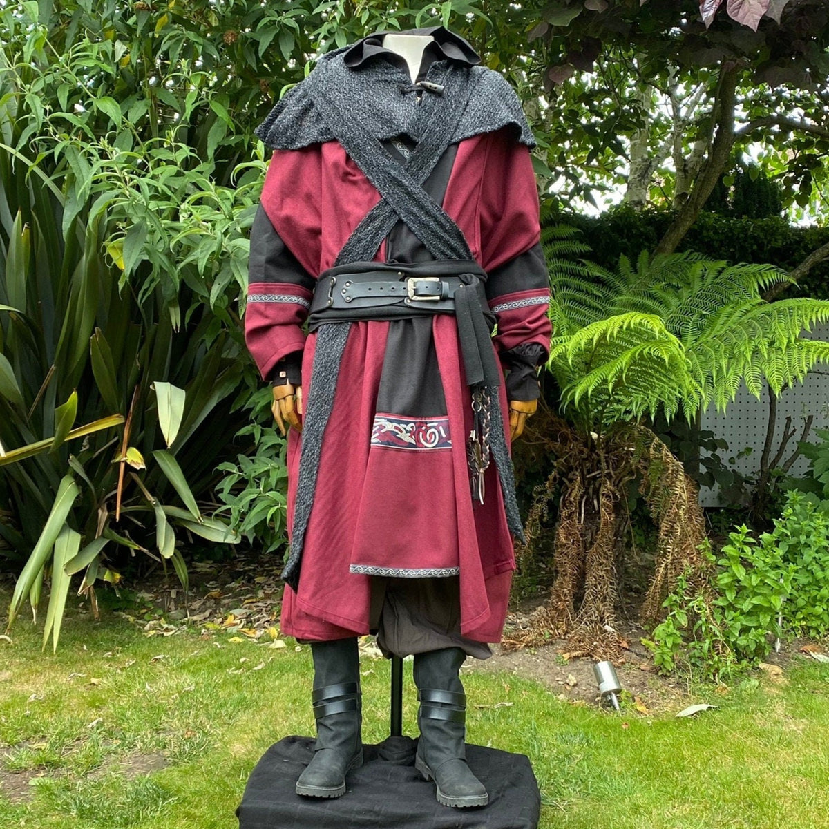 Medieval LARP outfit with red tunic, layered belts, and boots.