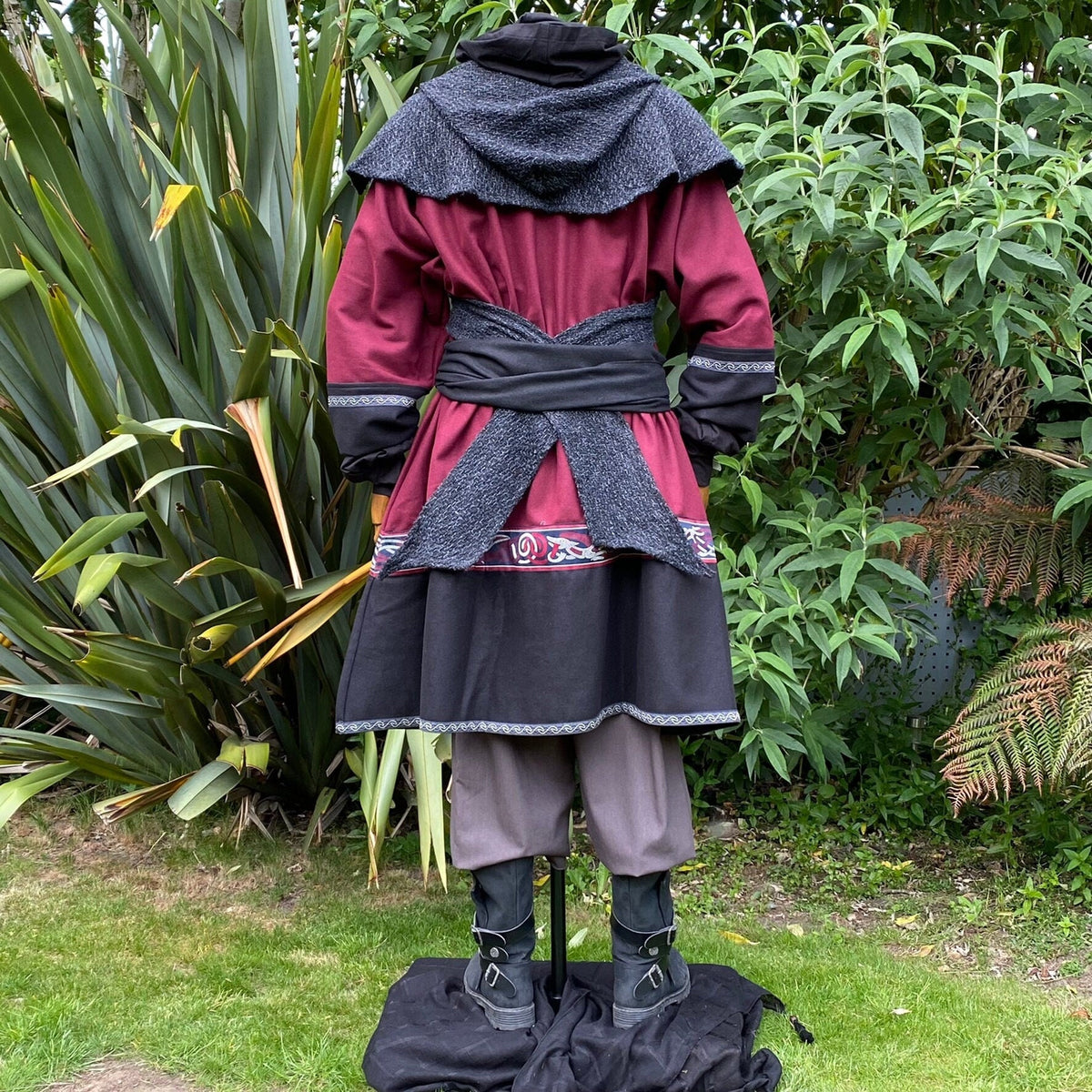 Back view of medieval LARP costume in red and black with intricate trim.