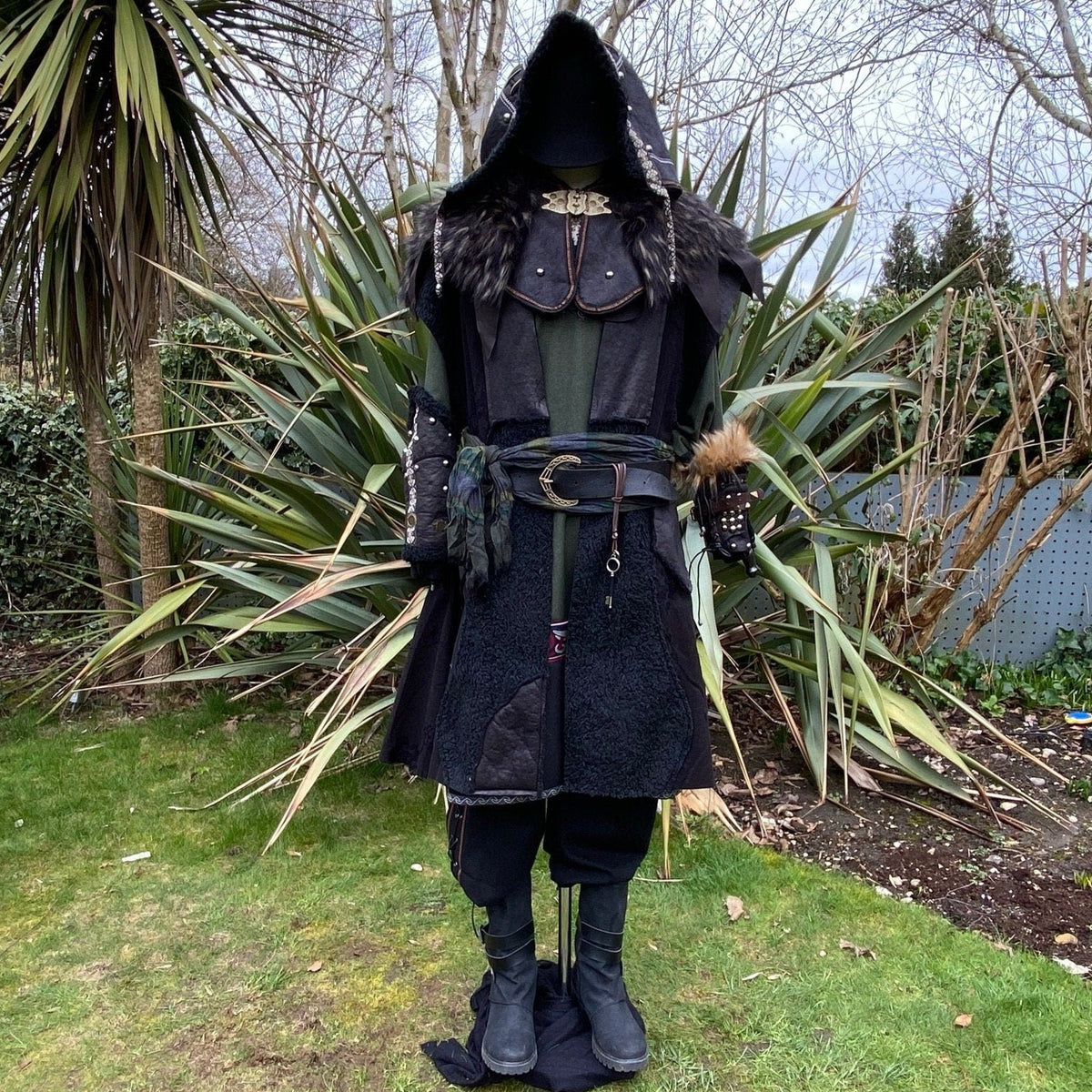 LARP medieval outfit front view; black hooded coat and fur-accented vambraces.