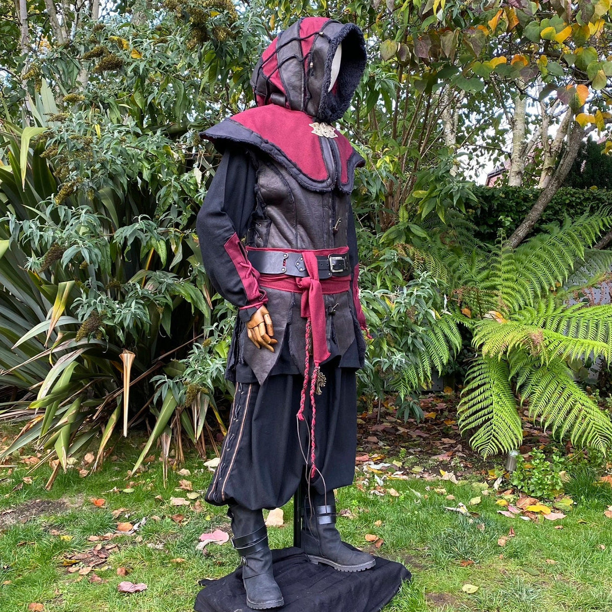 Medieval LARP outfit side view, featuring a red and black hood, waistcoat, shirt, belt and sash.