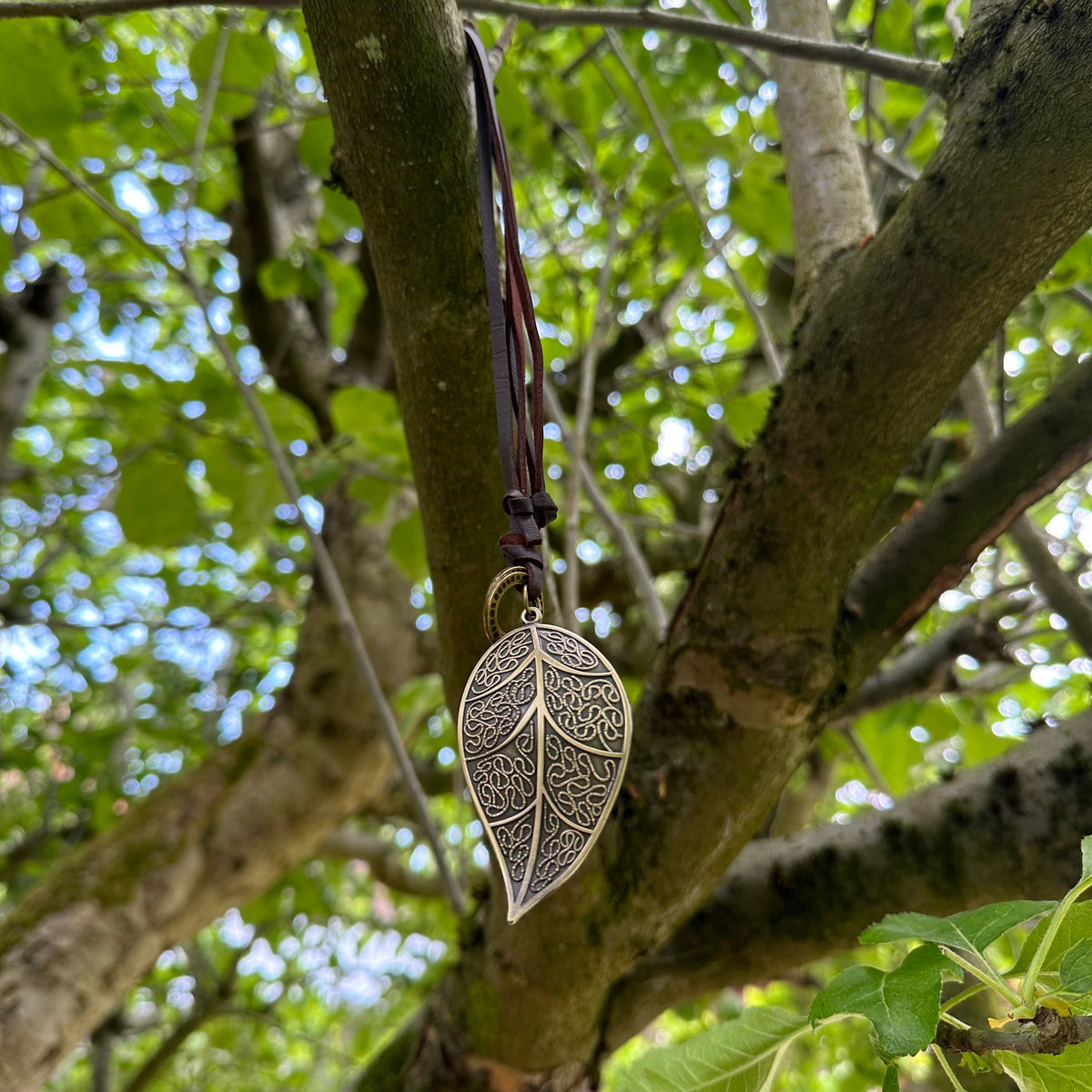 Intricate brass leaf necklace hanging in a tree for LARP or medieval wear.