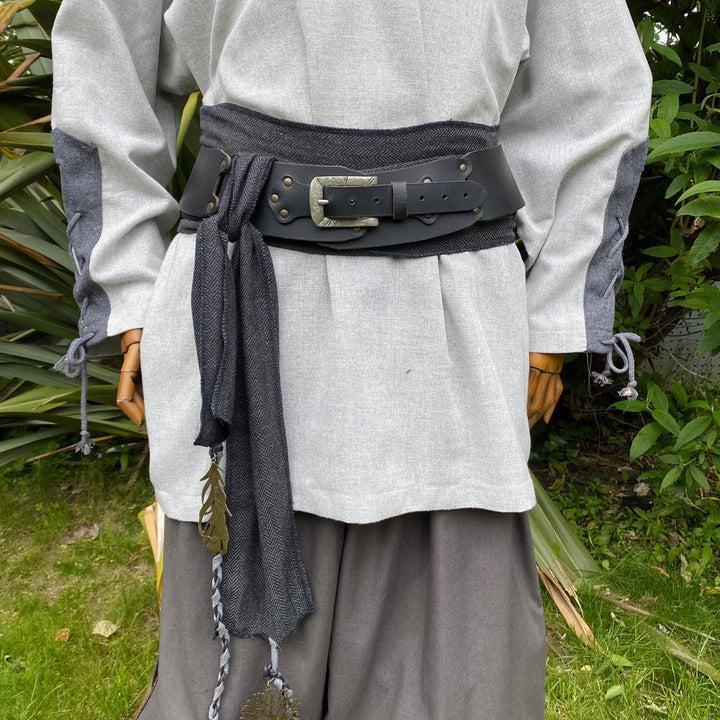 A LARP Belt and Costume Sash Set. The LARP Belt is made from Buffalo Leather in Black. The Viking Sash is a Black & Grey Herringbone Wool sash that works well by itself, or underneath the LARP Belt. The Medieval Sash has a decorated metal accessories that adds to your LARP Character, Cosplay, or Ren Faire event.