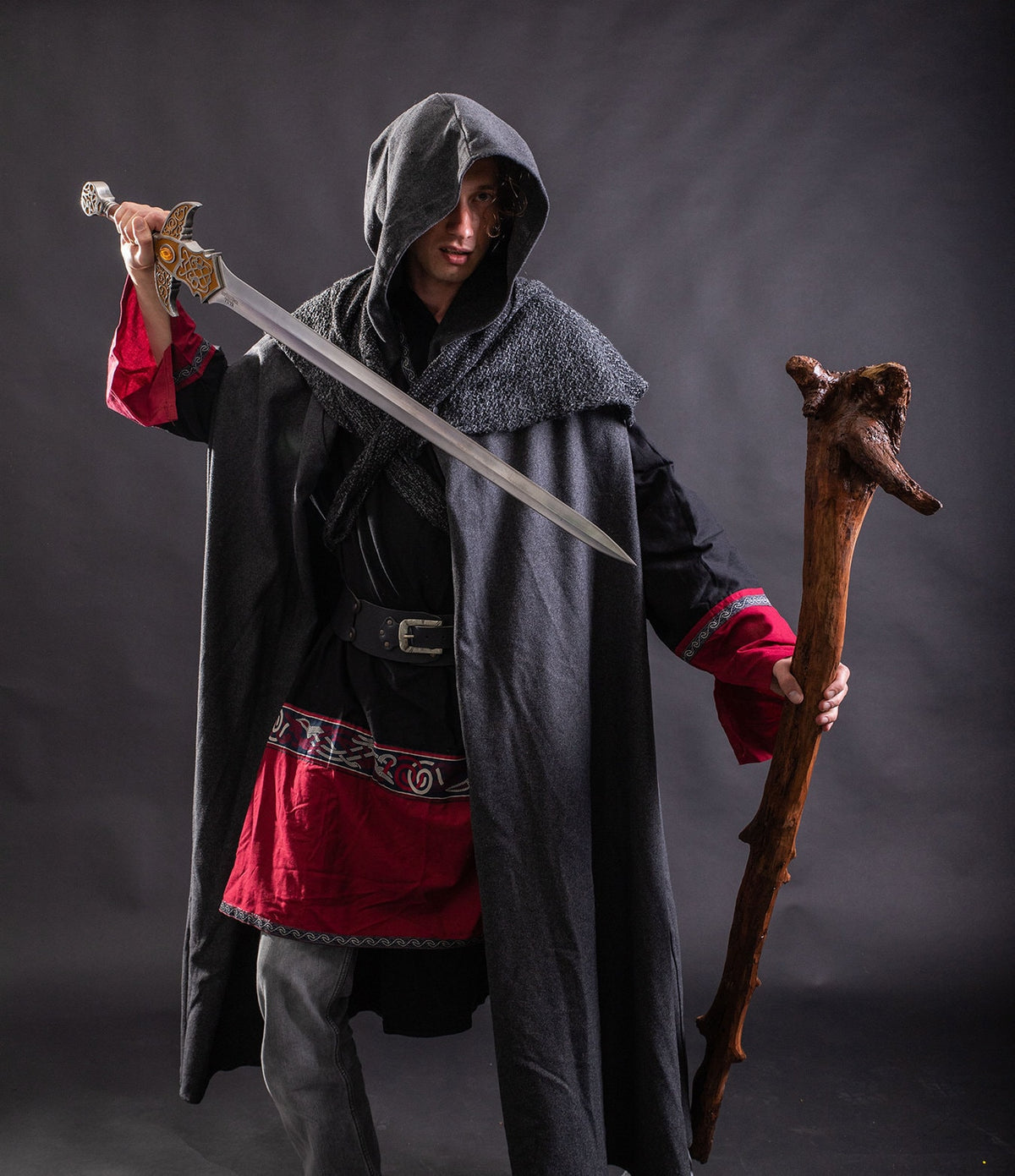 Model wearing hooded grey LARP cloak with sword raised, medieval fantasy cosplay costume for.